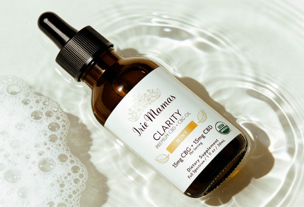 Irie Mamas Clarity premium CBD oil tincture with dropper on clear glass dish with water droplets. Organic full-spectrum 15mg CBG and 15mg CBD per serving mint flavor. Natural stress relief and mental clarity supplement.